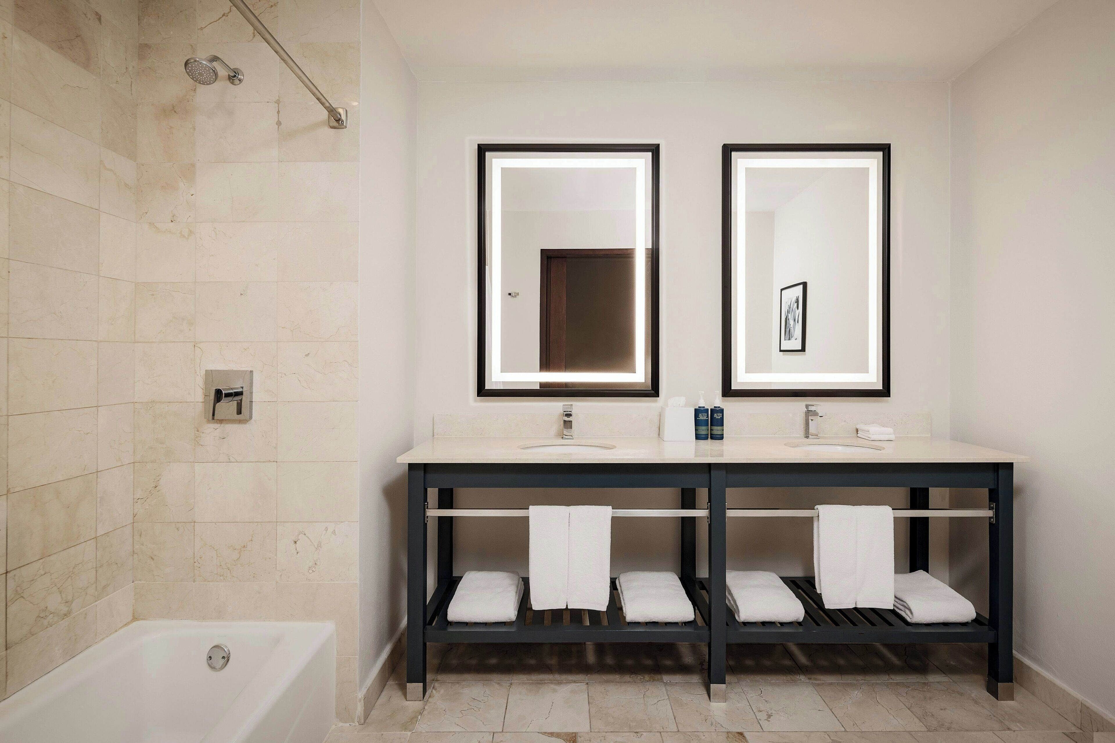 Ein modernes Badezimmer mit einer Badewanne, einem doppelten Waschbecken und zwei Spiegeln.