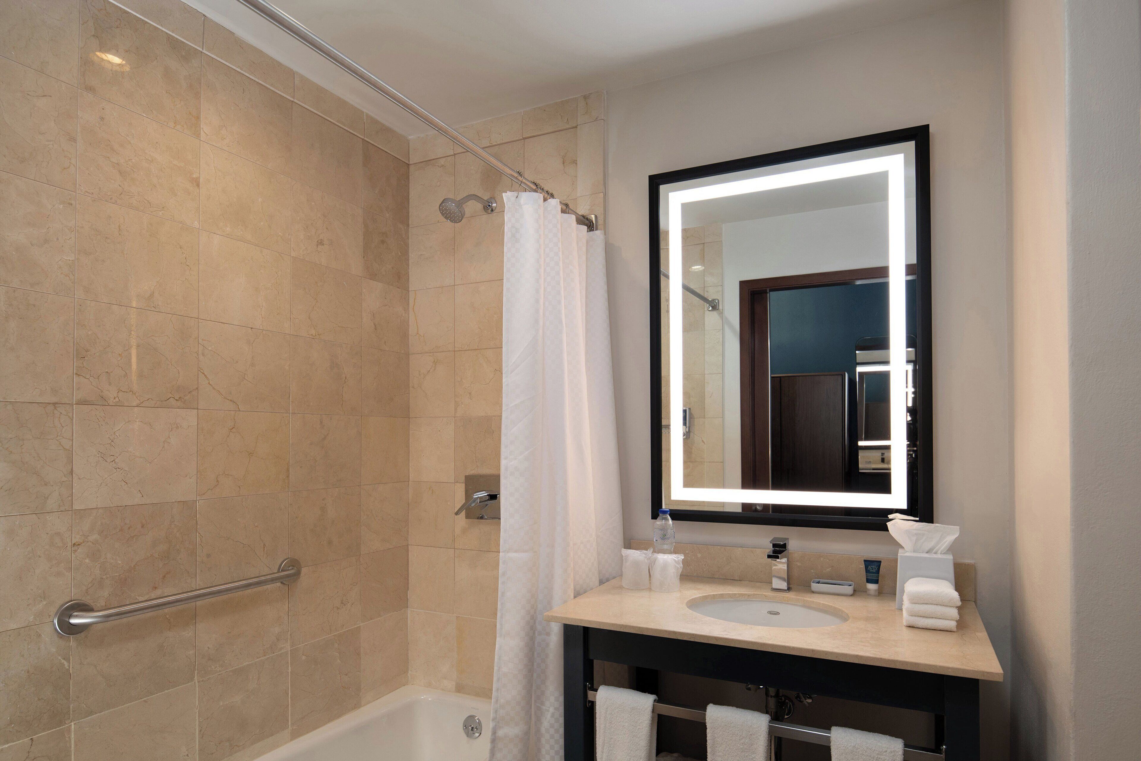 A modern bathroom with a bathtub, a shower with a glass door, a vanity with a mirror, and a towel rack.