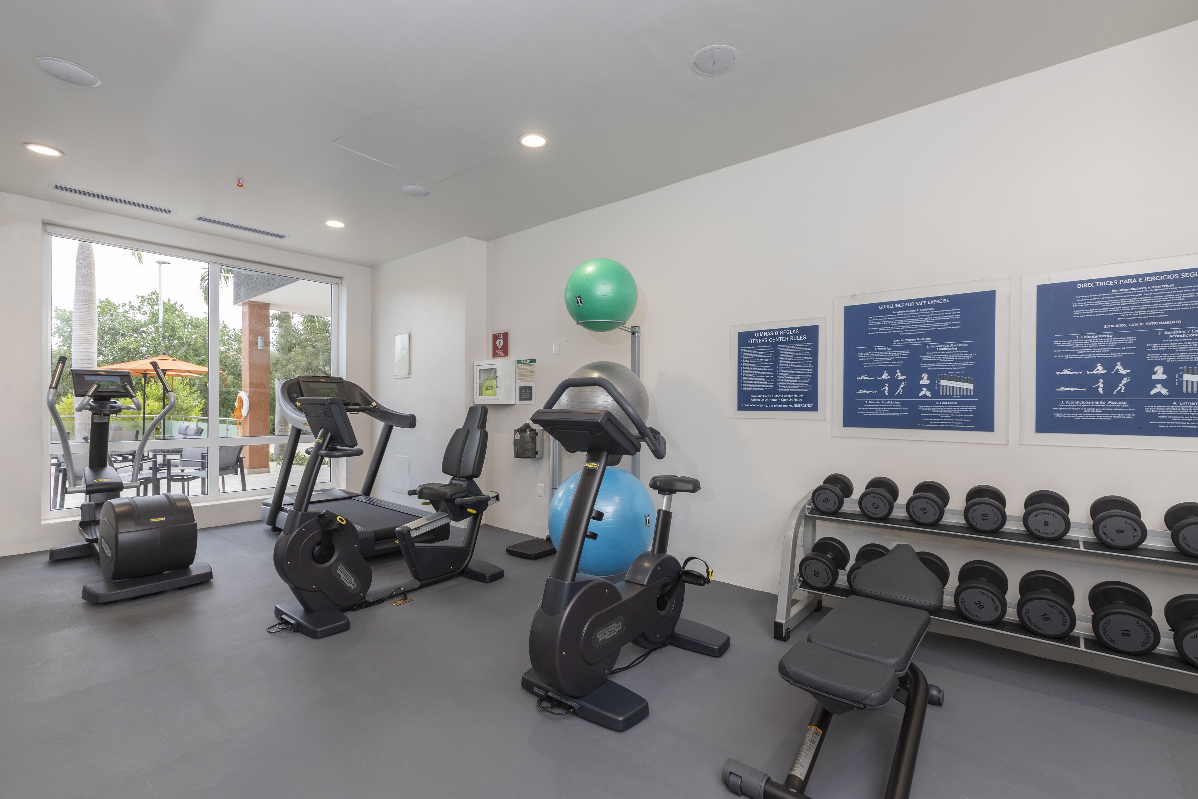 A gym with cardio machines, dumbbells, and exercise balls.