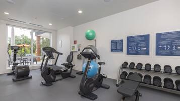 A gym with cardio machines, dumbbells, and exercise balls.