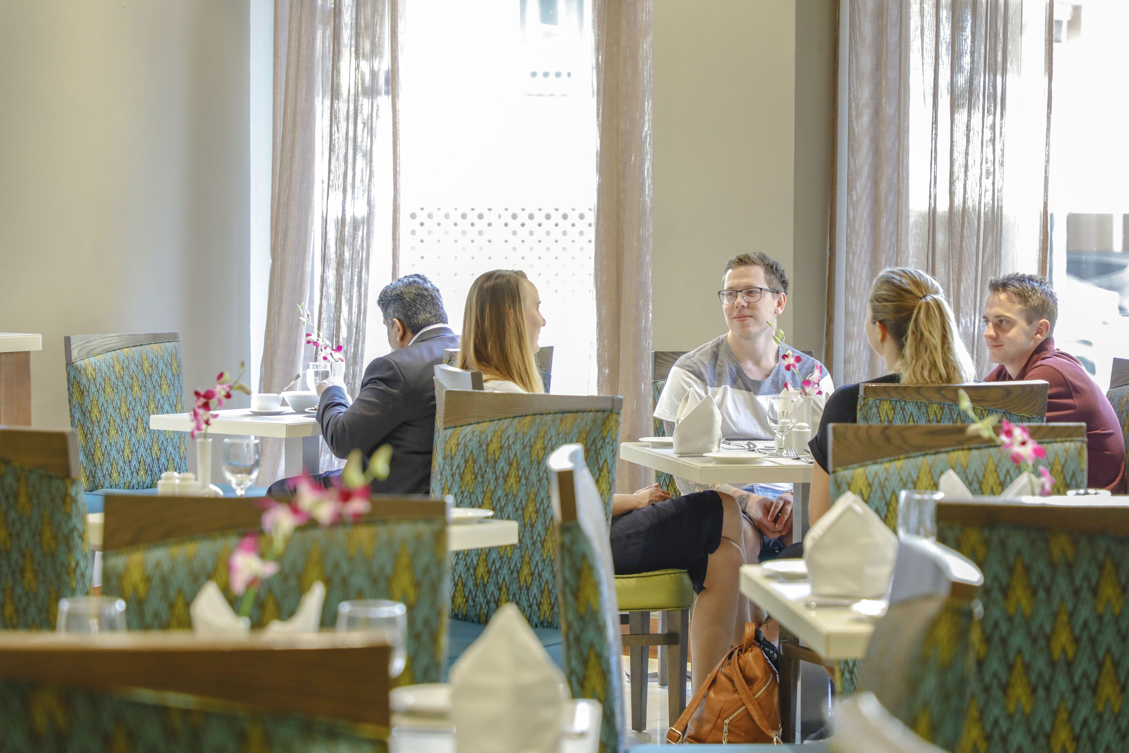 Un restaurante con mesas y cabinas, algunas adornadas con flores.
