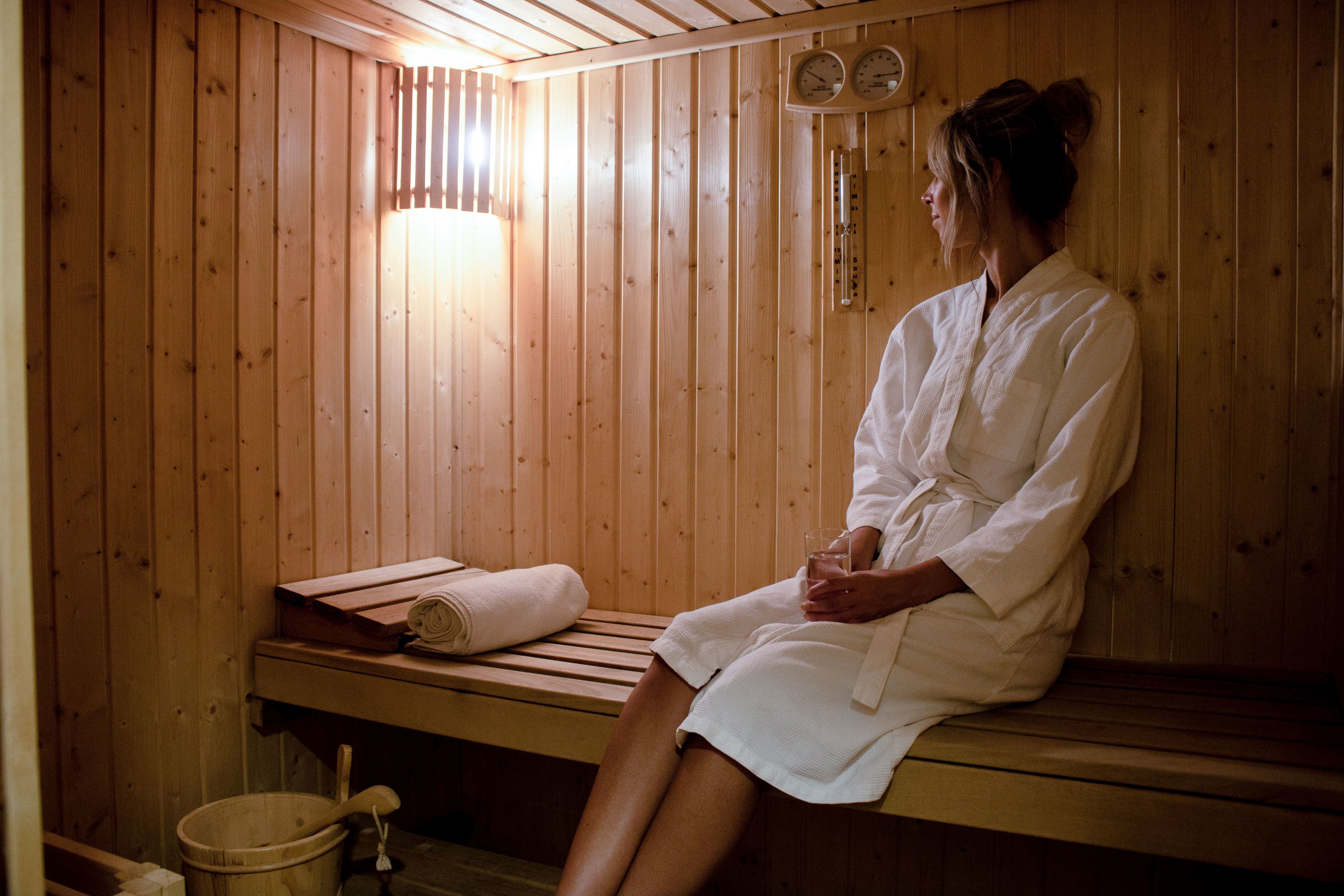 A wooden sauna with a bench, a towel, and a bucket.