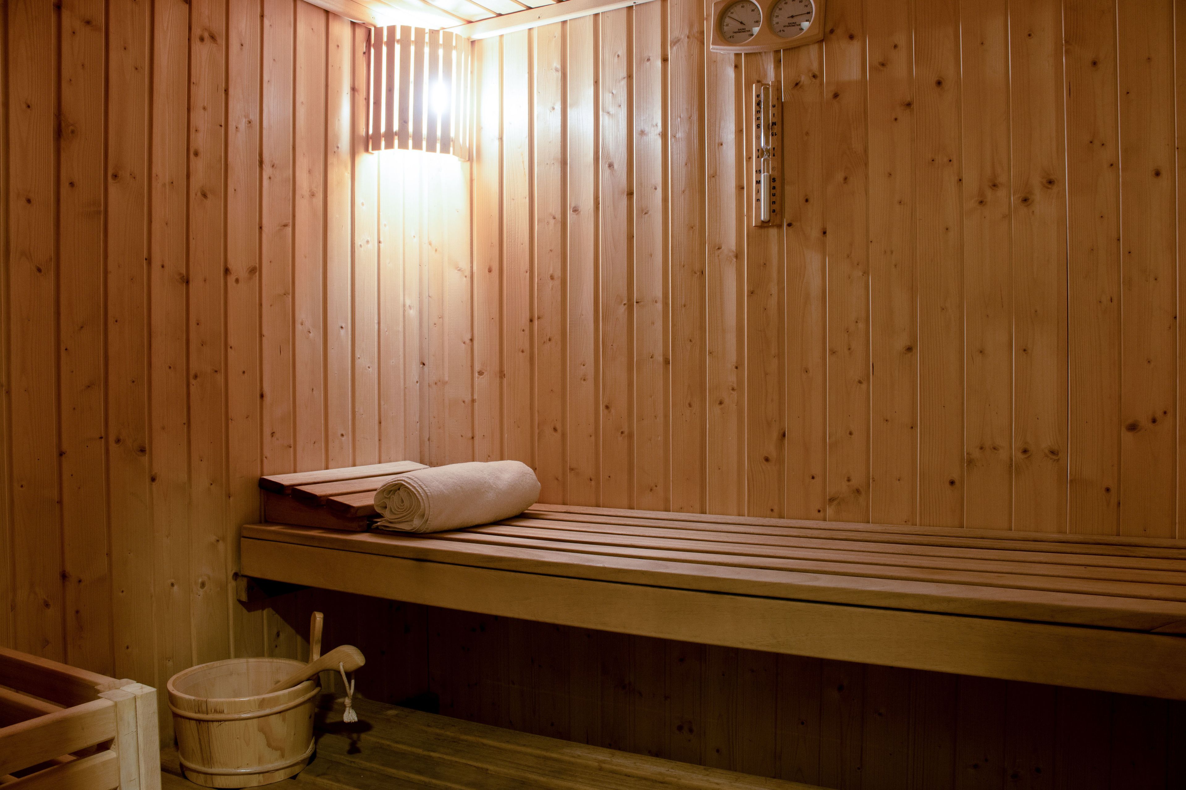 Una sauna de madera con un banco, un cubo y una toalla.