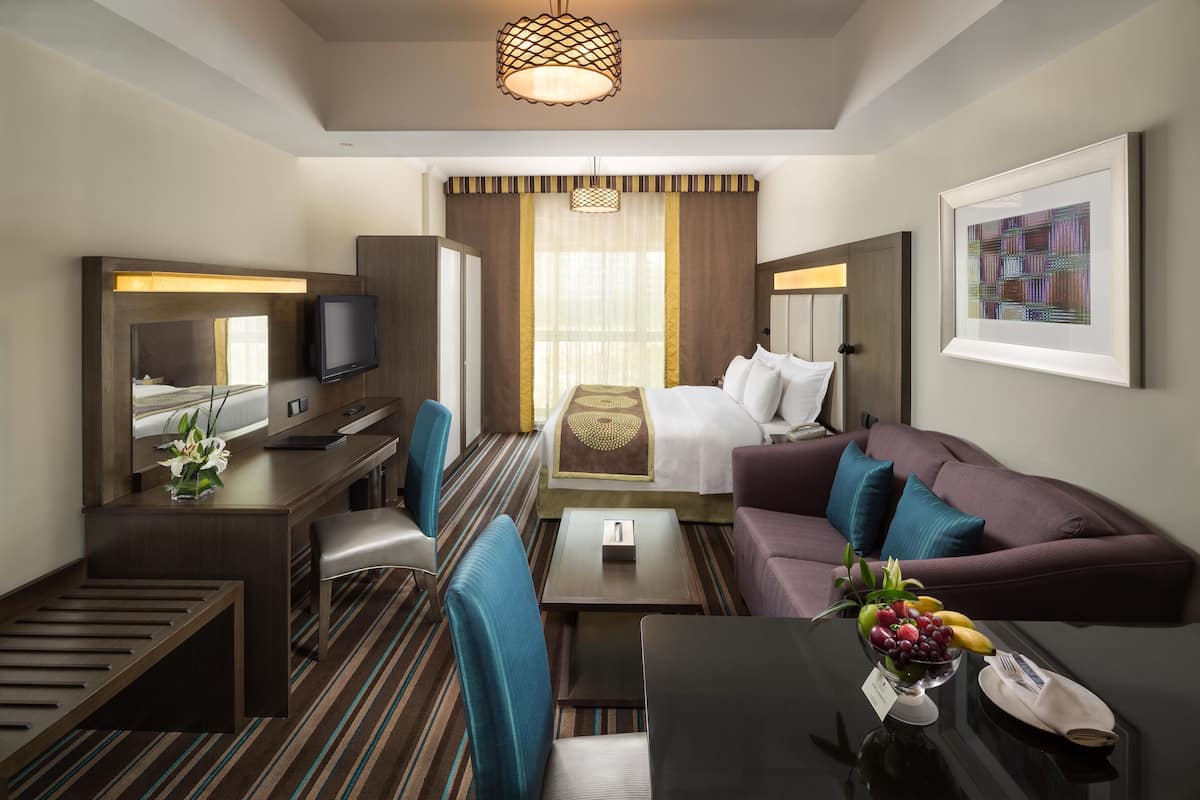 Une chambre d’hôtel comprenant un lit, un bureau avec un ordinateur, un canapé et une table basse.