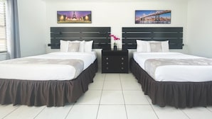 A hotel room with two beds, a ceiling fan, and two paintings of cityscapes. - Hollywood Beach Blue Wave (Hollywood)