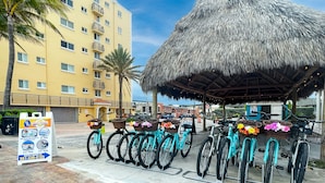A beachfront hotel with a thatched-roof structure, bicycles with baskets, and a rental sign. - Hollywood Beach Blue Wave (Hollywood)
