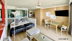 Une chambre d’hôtel moderne équipée d’un lit, d’un coin repas et d’une télévision.