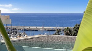 A marina with boats docked, a clear blue sky, and a view of the ocean. - Porlamar (Mogan)