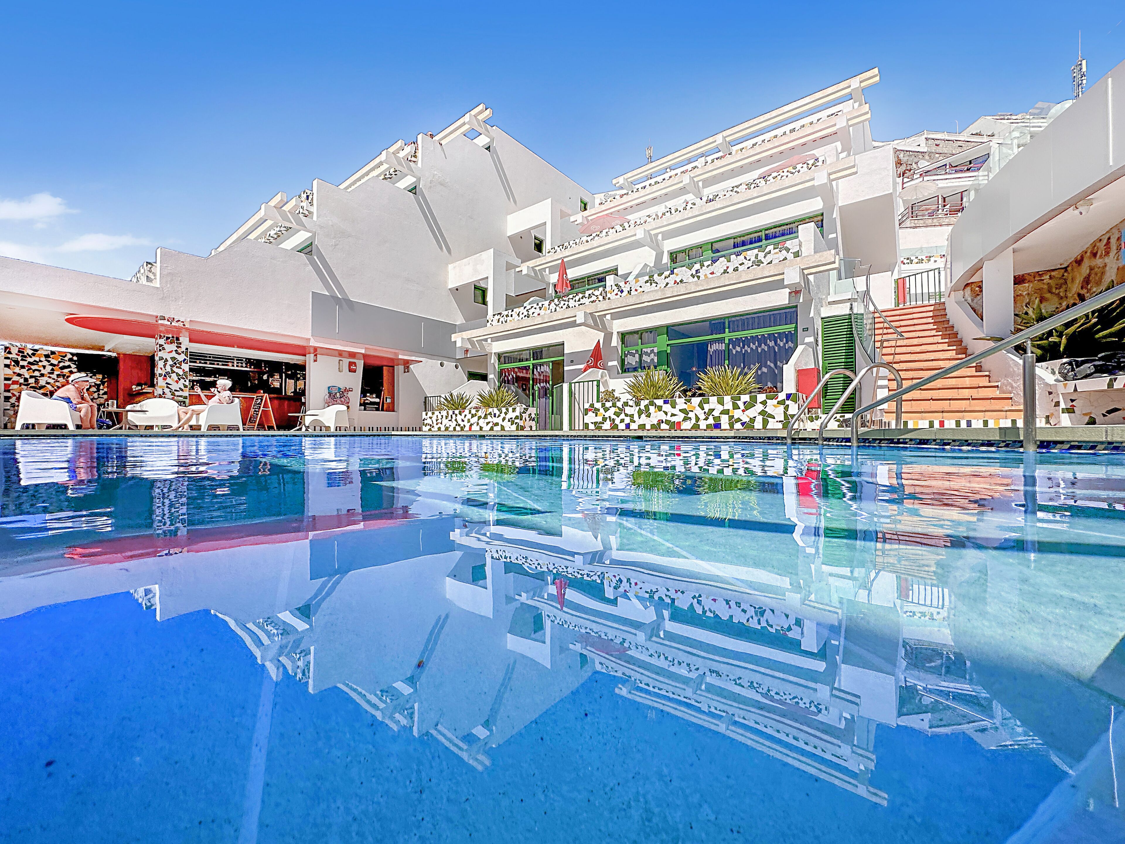Un hôtel moderne doté d’une piscine, d’un espace extérieur aménagé et d’un bar.