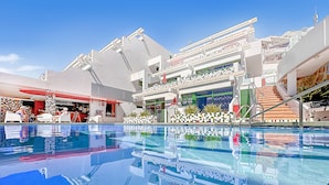A modern hotel with a swimming pool, outdoor seating, and a bar area. - Porlamar (Mogan)