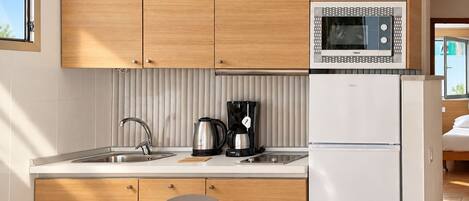 Una cucina moderna con mobili in legno, un lavello in acciaio inossidabile, un bollitore, una macchina da caffè e un frigorifero bianco.
