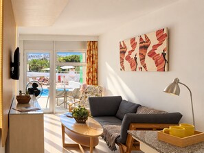 Una sala de estar moderna con un sofá, una mesa de centro, un televisor y un cuadro.