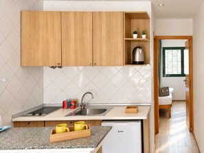 Una cocina moderna con armarios de madera, un lavamanos de acero inoxidable y una cafetera integrada.