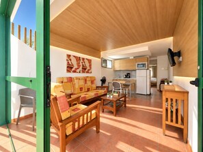 A compact living space with a sofa, dining table, and kitchenette. - Leticia Del Mar (Mogan)