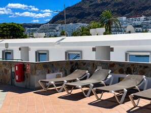 Terraza en la azotea con sillones de descanso y un muro de piedra.