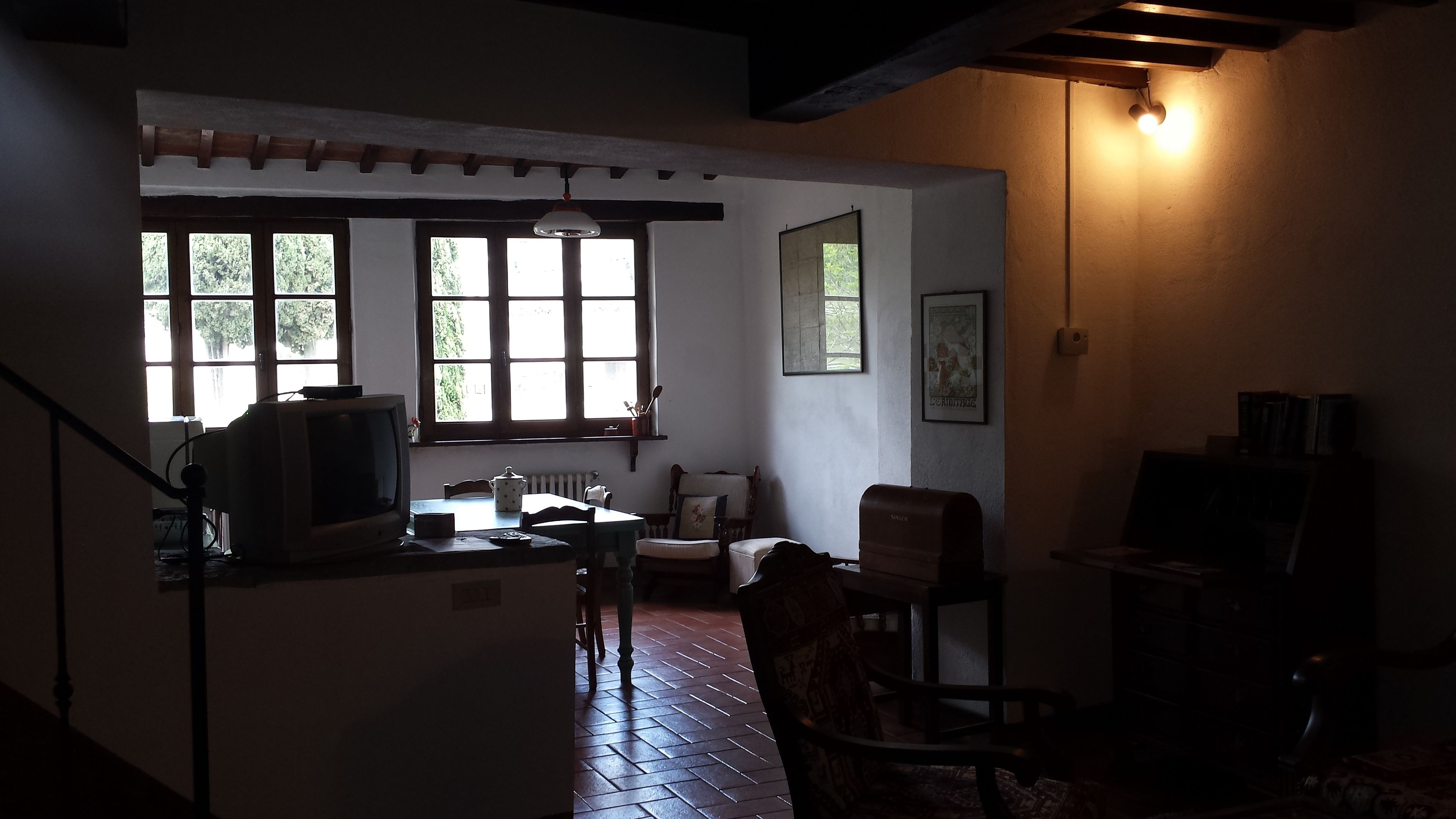 Une pièce faiblement éclairée, avec une télévision, une chaise, une table et une bibliothèque.
