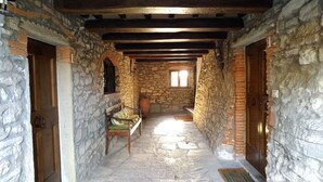 Un estrecho pasillo de piedra con puertas de madera y un banco.