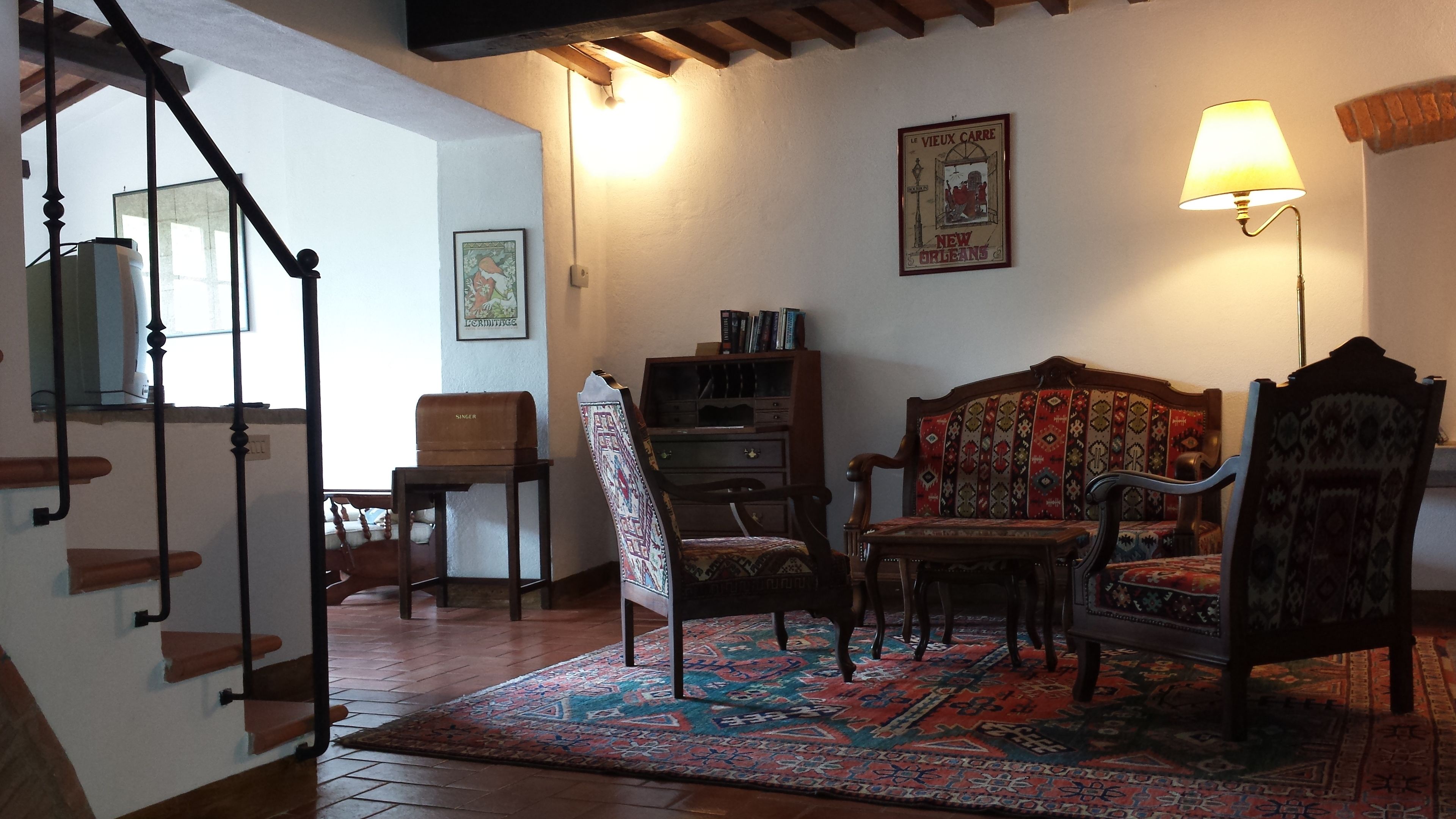 Un salon chaleureux avec un tapis à motifs, une chaise en bois, un canapé et une bibliothèque.