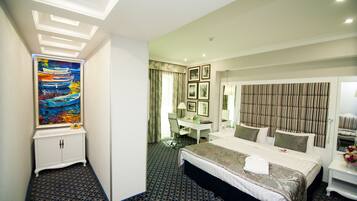 A hotel room with a bed, desk, and a painting on the wall.