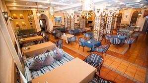 Un restaurante con varias zonas de estar, incluyendo mesas y cabinas, un suelo de baldosas e iluminación decorativa.