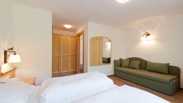 Un dormitorio con una cama, un sofá verde, un armario de madera y un espejo.