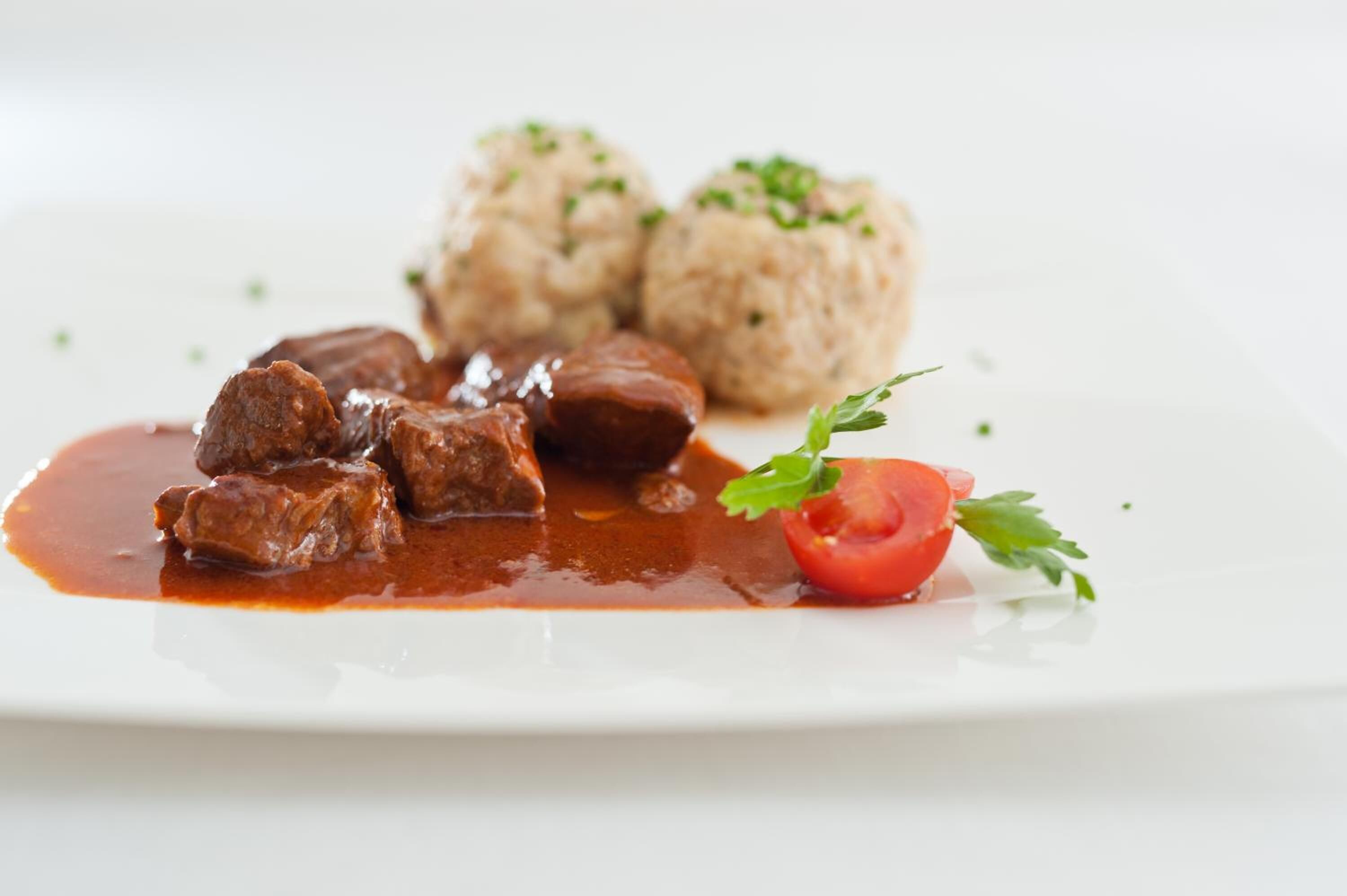 Un plato con albóndigas, una rodaja de tomate y decoración.