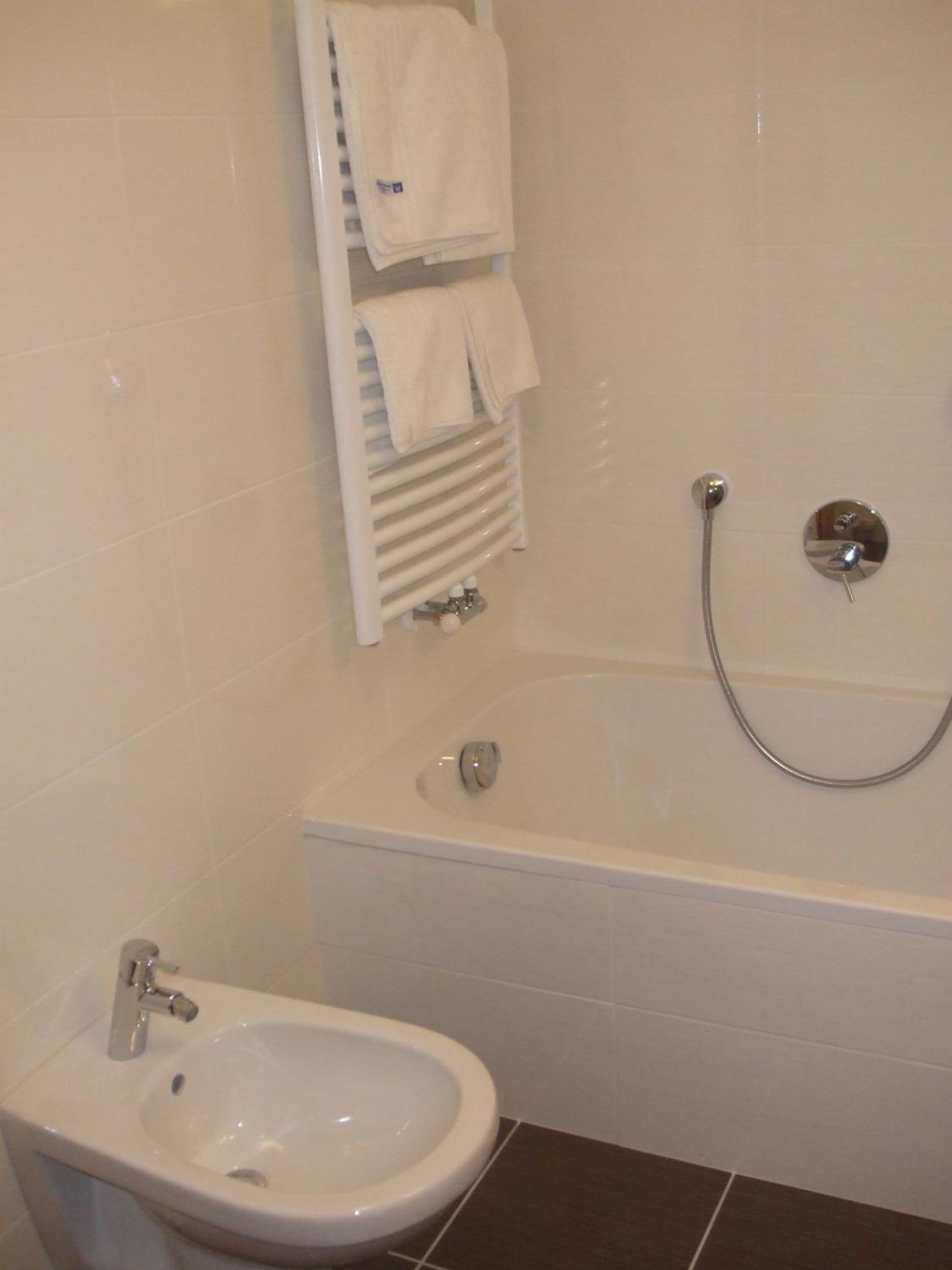 Un baño con bañera, un bidé y un perchero para toallas.