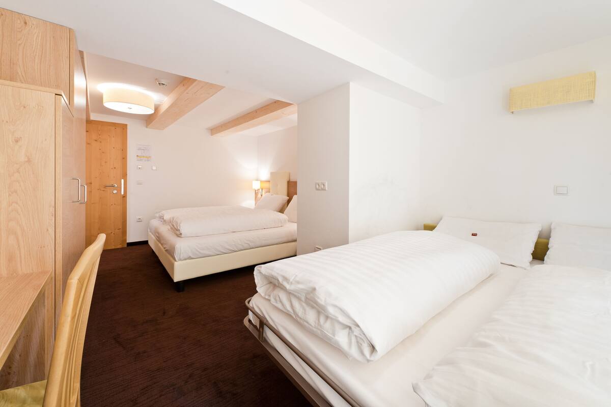Ein Hotelzimmer mit zwei Betten, Holzmöbeln und einer Decke mit freiliegenden Balken.