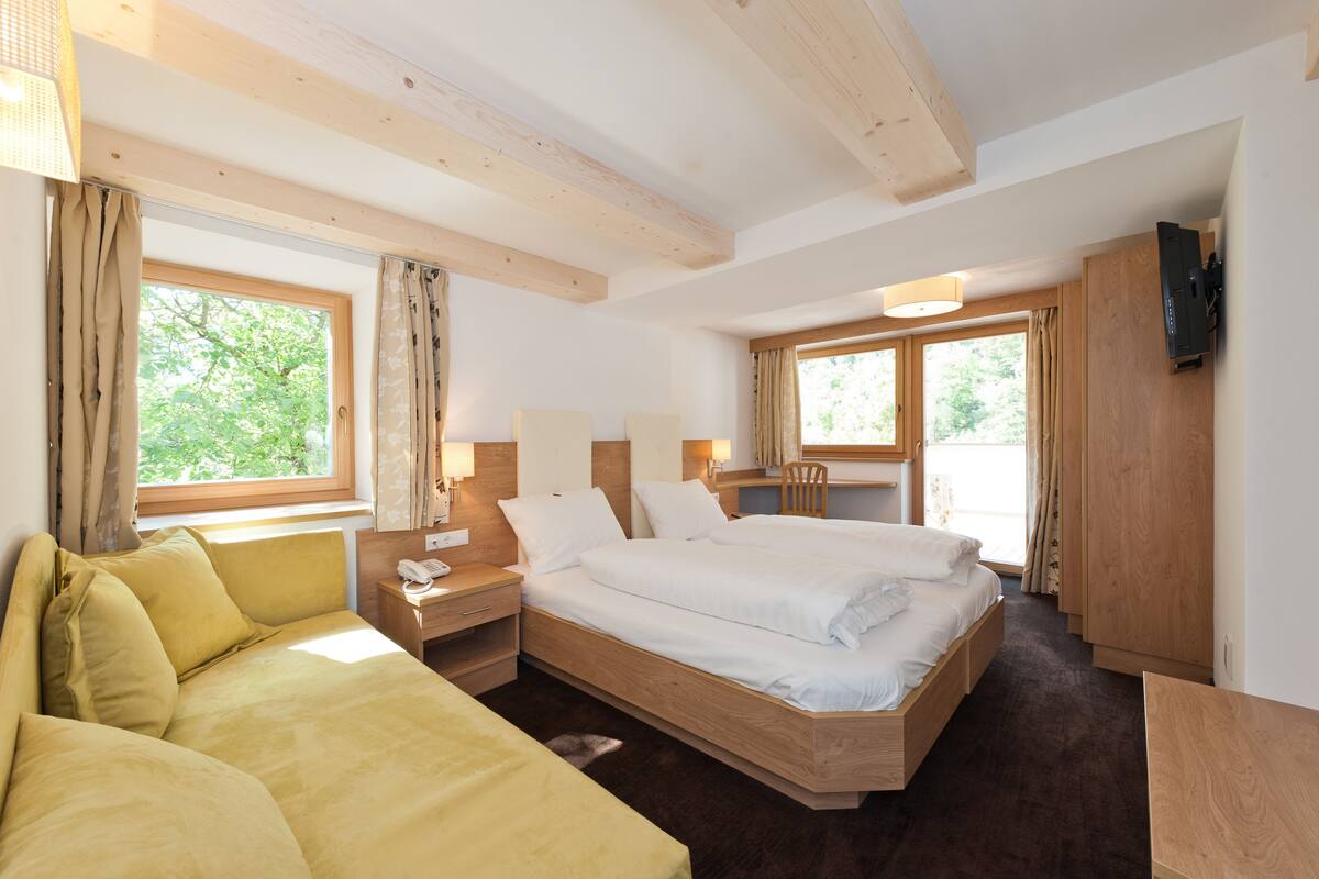 Ein Hotelzimmer mit einem großen Bett, einer Couch, einem Schreibtisch und einem Fernseher.