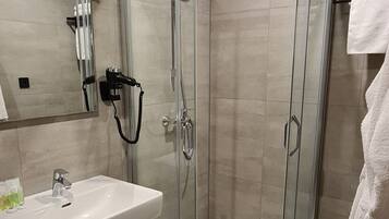 A modern bathroom with a glass-enclosed shower, a sink, and a towel rack.