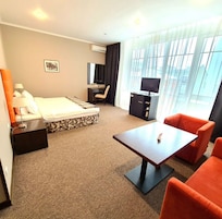 Habitación de hotel con cama, escritorio, televisión y zona de estar con mesa y sillas.