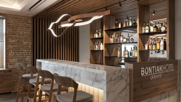 Un área de bar con mostrador de mármol, sillas de madera y un panel de listones de madera.