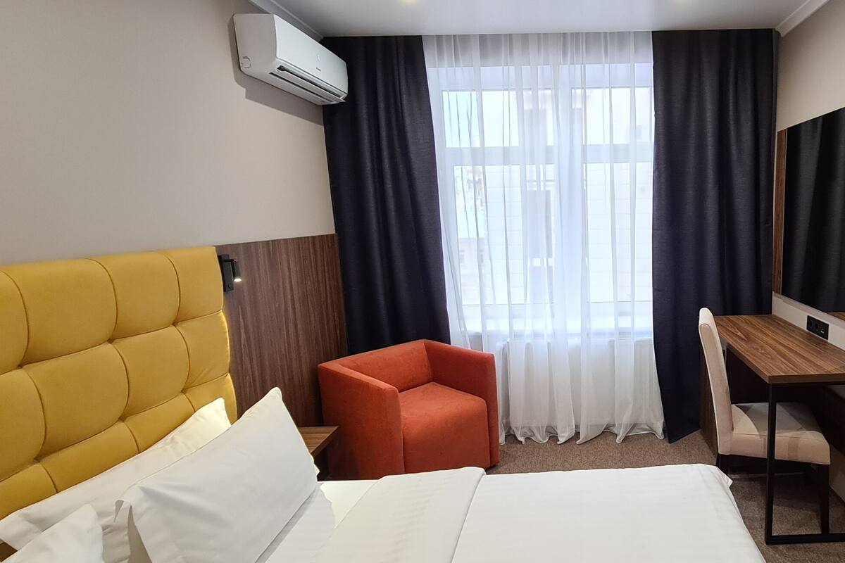 Una habitación de hotel con cama, escritorio, silla y televisor.