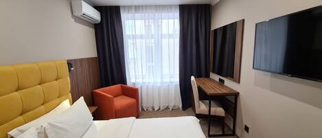 Una habitación de hotel con cama, escritorio, silla y televisor.