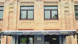 Un edificio de ladrillo con tres entradas, cada una señalada por un toldo negro con el nombre 'Bontiak Hotel' y la dirección 'Ucrania KYIV'.