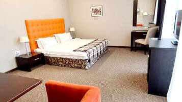 A hotel room with a bed, a desk, a chair, and a TV.