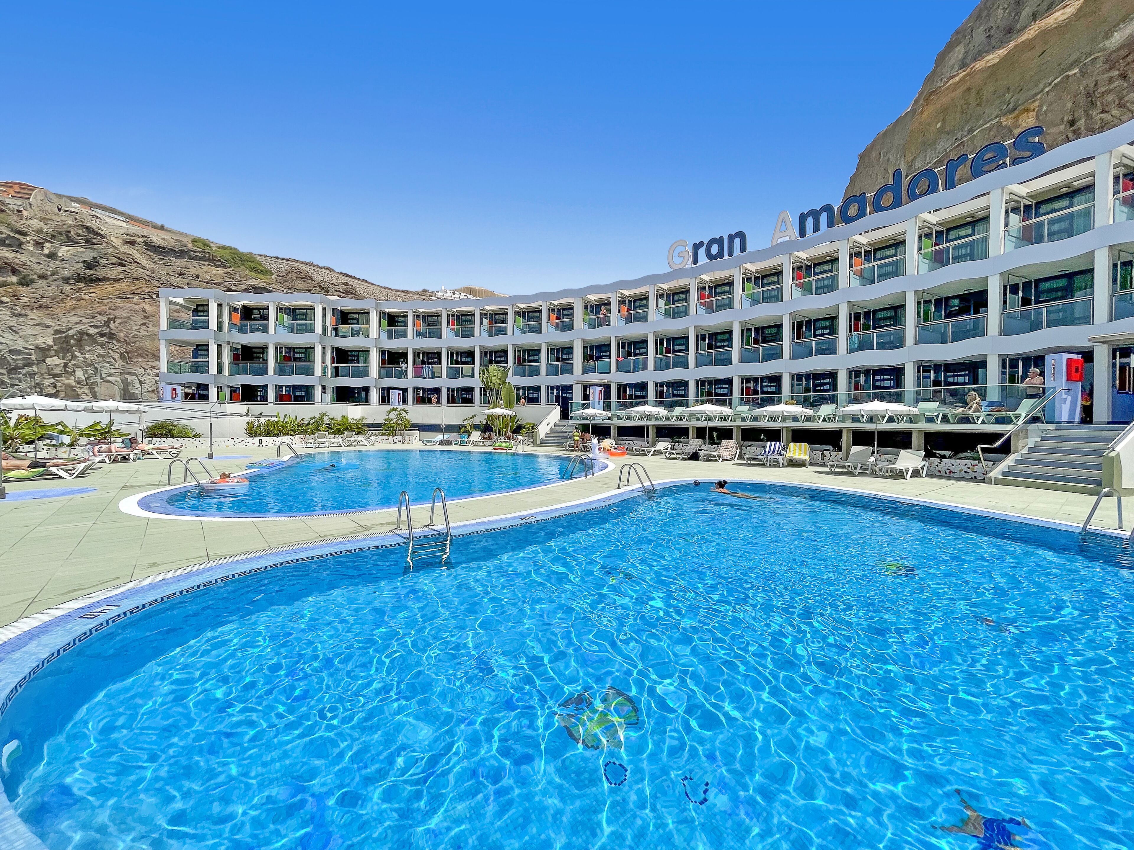 Un hôtel doté d’une grande piscine, de nombreux balcons et offrant une vue imprenable sur les montagnes.