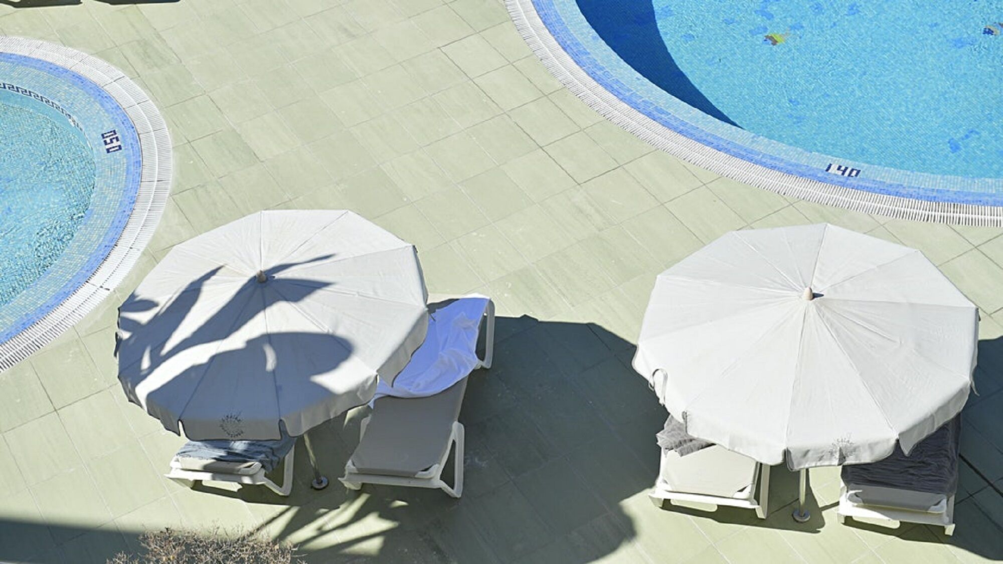 Un espace piscine équipé de deux parasols et de chaises longues.