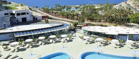 Una piscina al aire libre, sombrillas, tumbonas