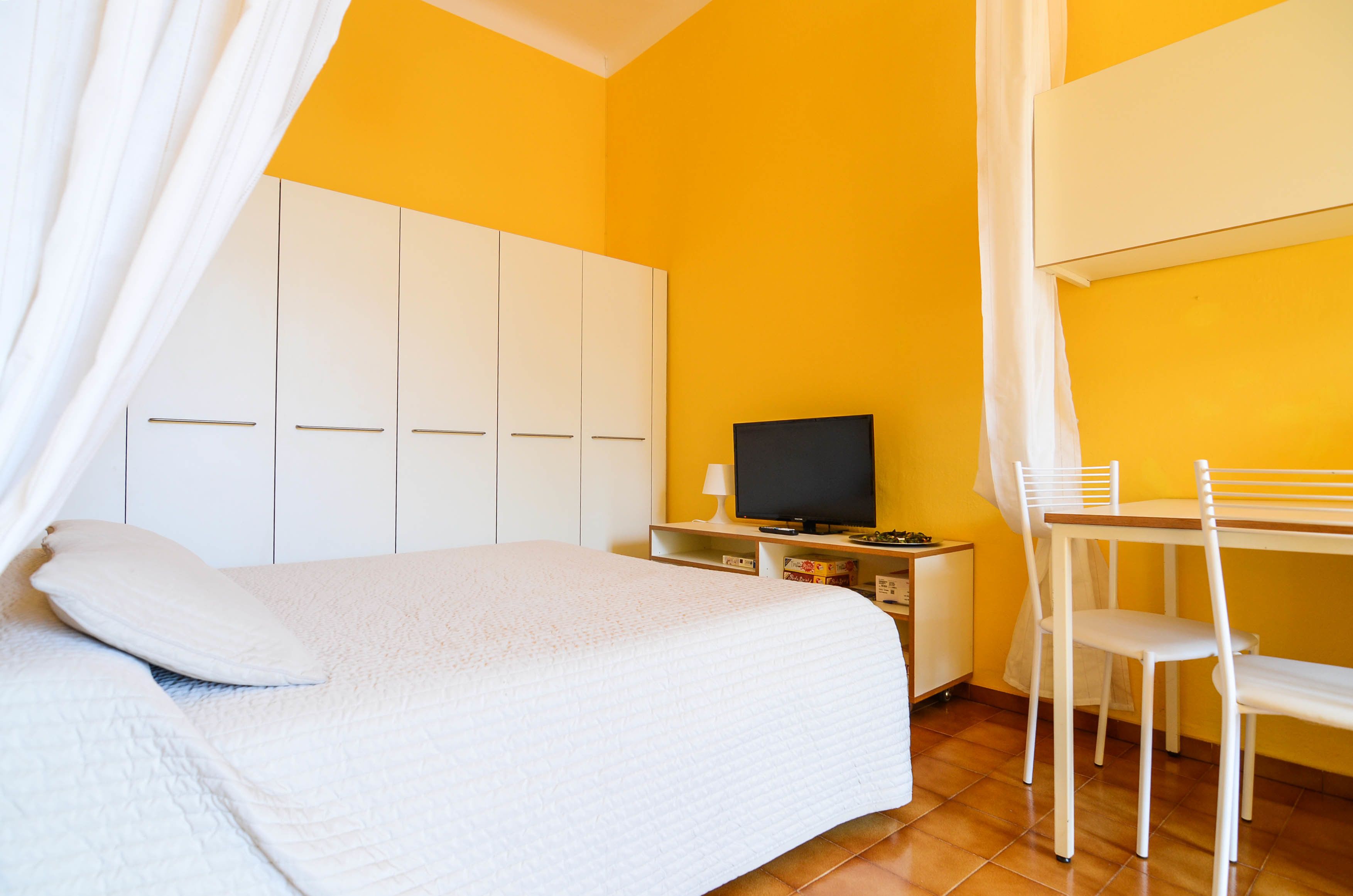 Une chambre comprenant un lit, une télévision, un bureau avec une chaise et une armoire.
