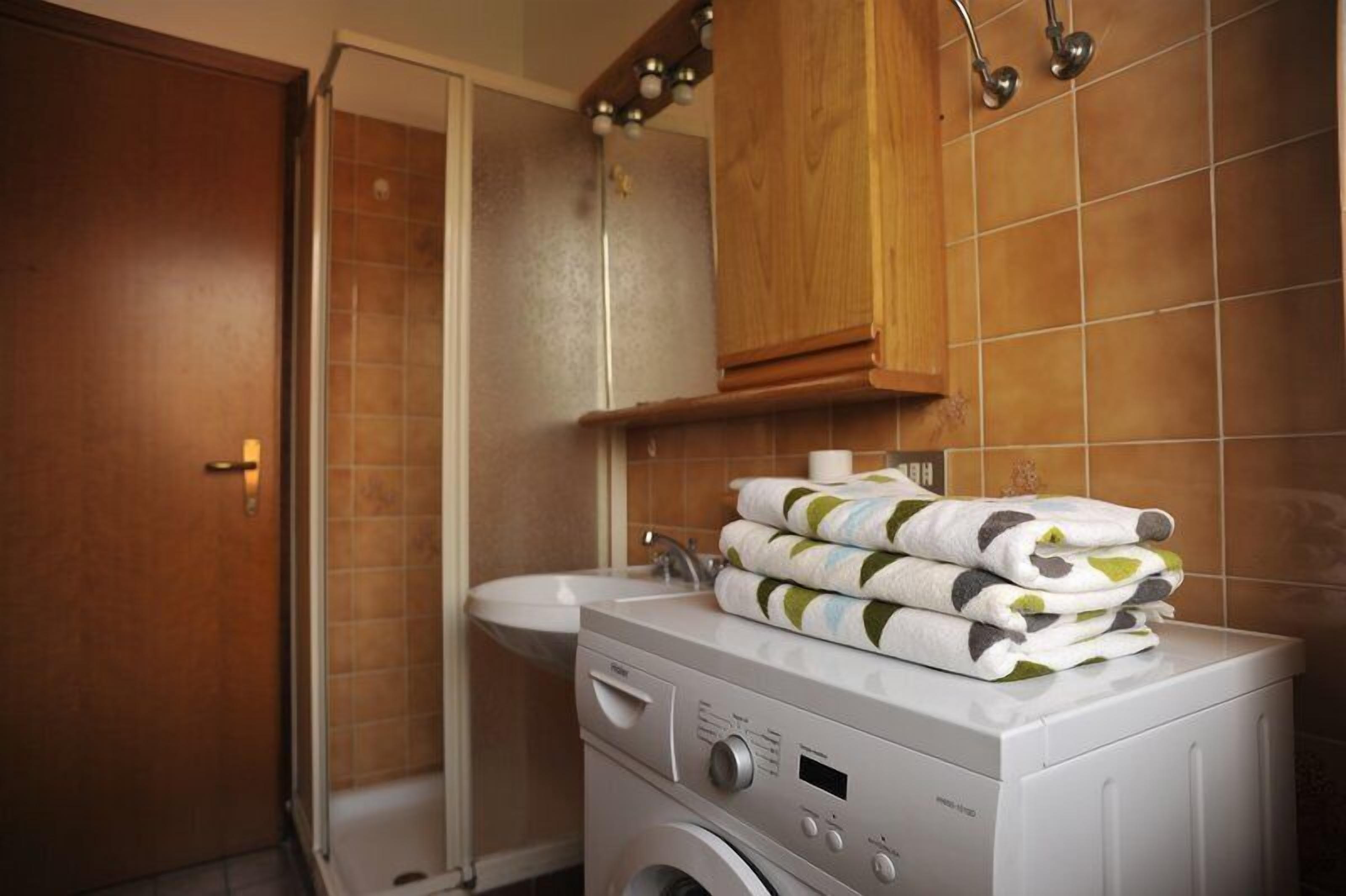 A laundry area with a washing machine, a sink, and a wooden cabinet.