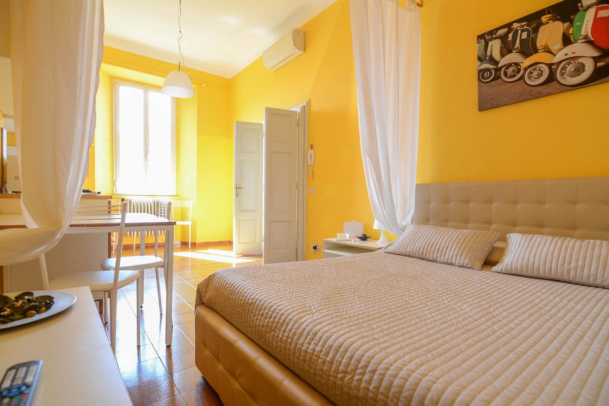 A hotel room with a large bed, a desk, and a chair.