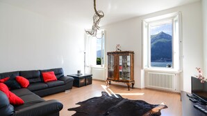 Ett modernt vardagsrum med en svart lädersoffa, ett träskåp och ett stort fönster med utsikt över bergen.