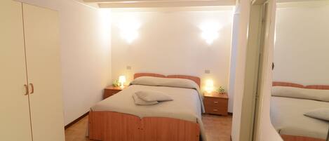 A bedroom with a wooden bed, bedside tables with lamps, and a wardrobe.