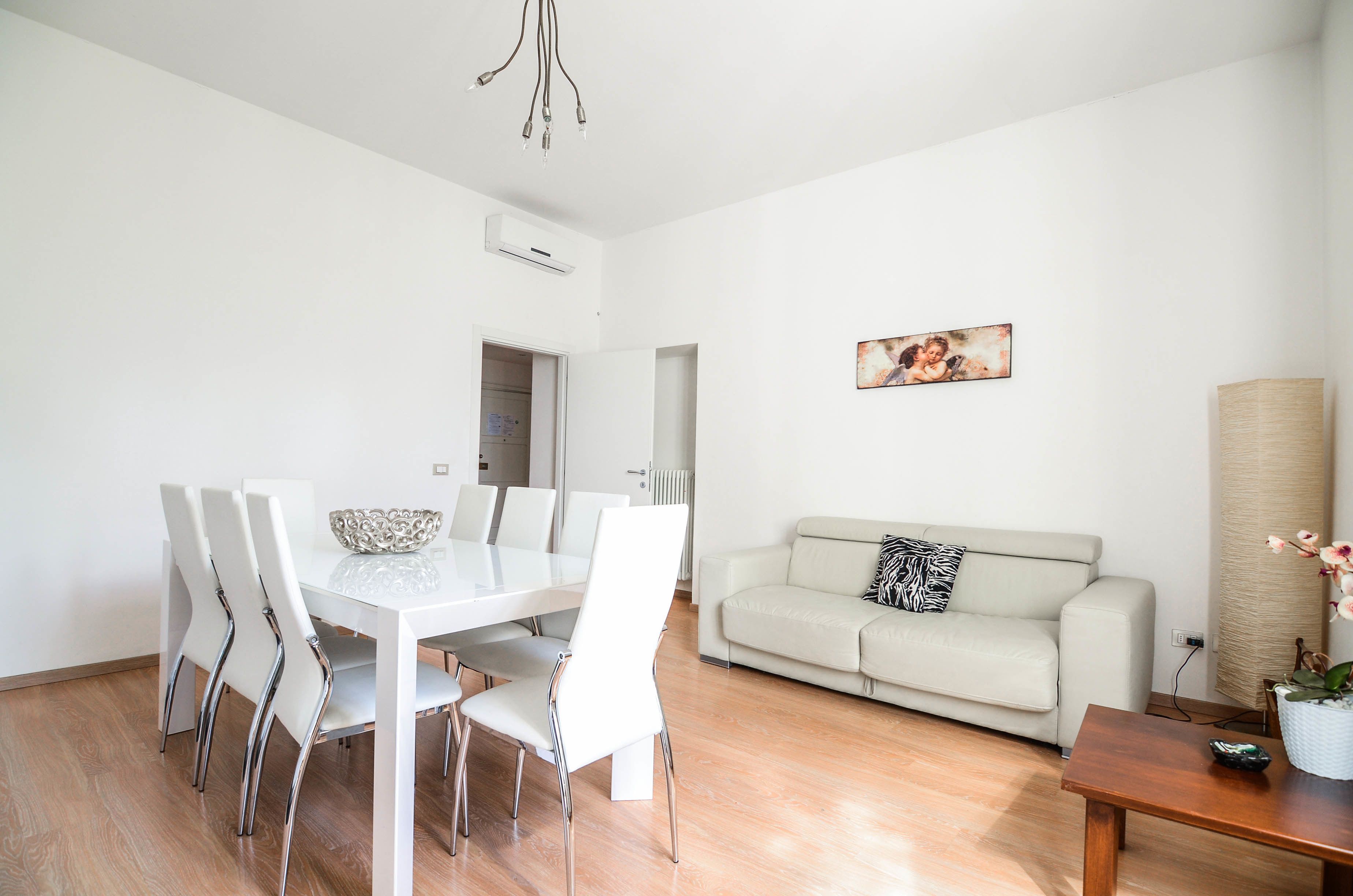 A modern living room with a dining table, white chairs, a sofa, and a coffee table.