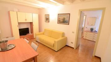 Un espacio habitable compacto con una mesa de comedor, un sofá, un televisor y una kitchenette.
