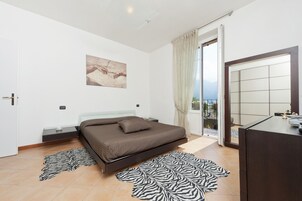 Una camera da letto con un letto, un comodino, uno specchio e vista sull'esterno.