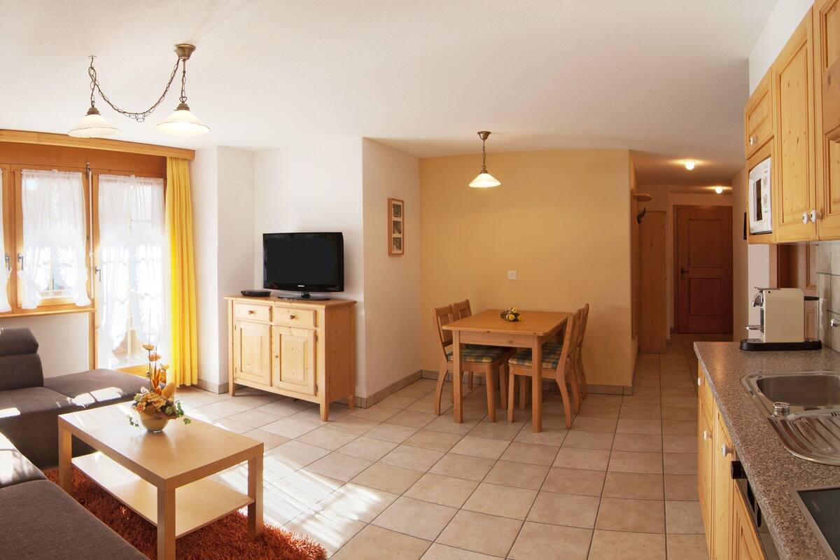 A compact living space with a sofa, a dining table, and a kitchenette.