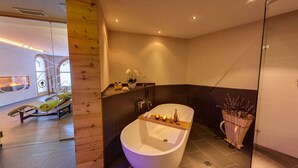 Un baño moderno con una bañera independiente, un tocador de madera y un espejo grande.