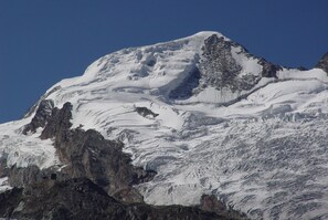A snow-covered mountain with rocky outcrops and a clear blue sky. - Arcade Apartments (Saas-Fee)